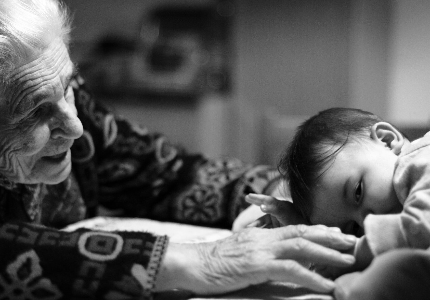 grandmother holding hand of baby who is resting